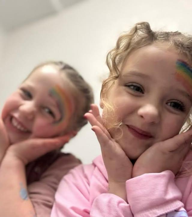 Friends with matching rainbow face paint at a pamper celebration