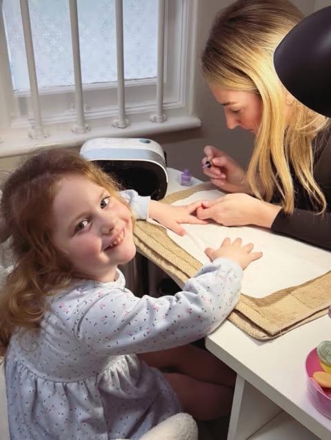 Girl smiling while receiving purple nail polish at her pamper party