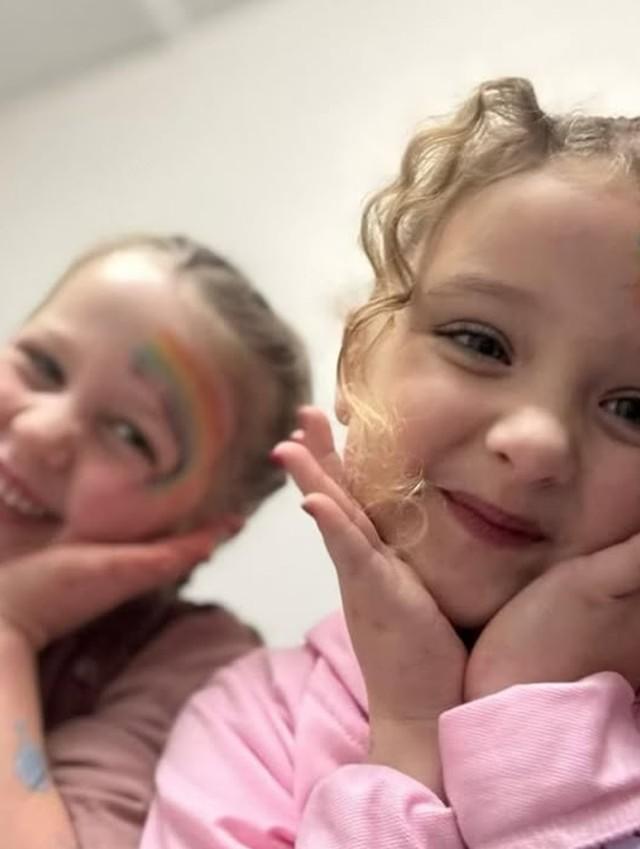 Girls with rainbow face paint smiling at a pamper party